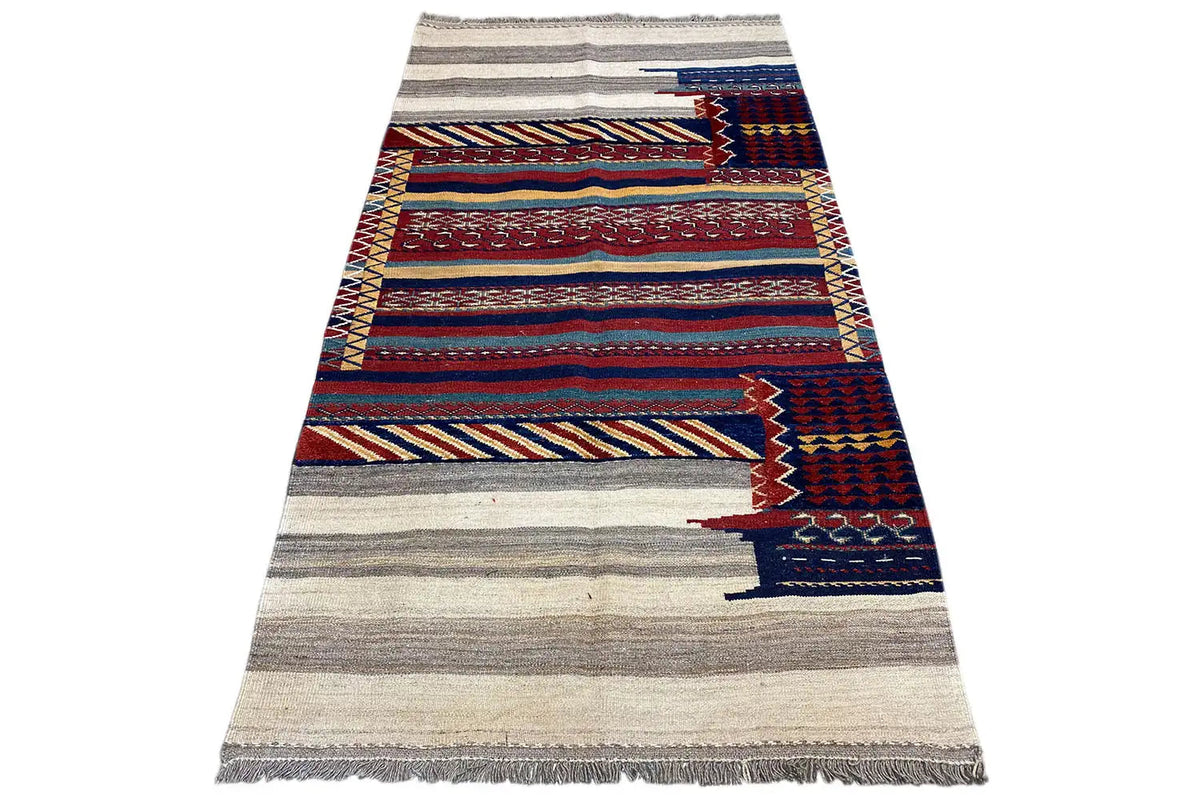 Kilim rug spread out, beige with red and blue border-style lines, fringed.