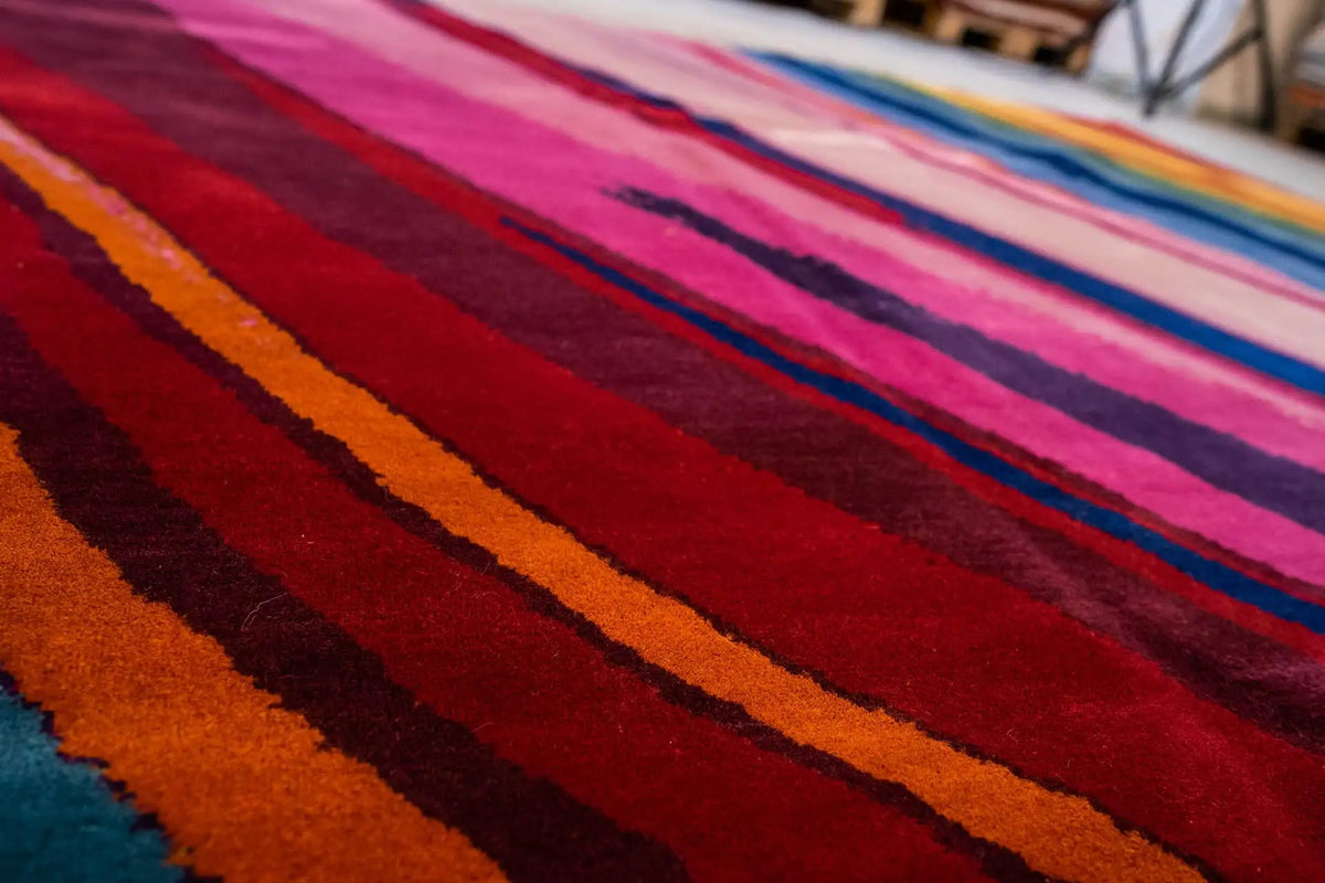 Colorful striped rug, diagonal bands of color from pink to blue