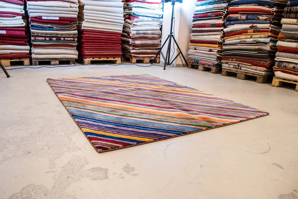 Designer rug on floor: multicolored stripes, laid out in a rectangle