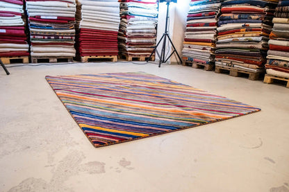 Designer rug on floor: multicolored stripes, laid out in a rectangle