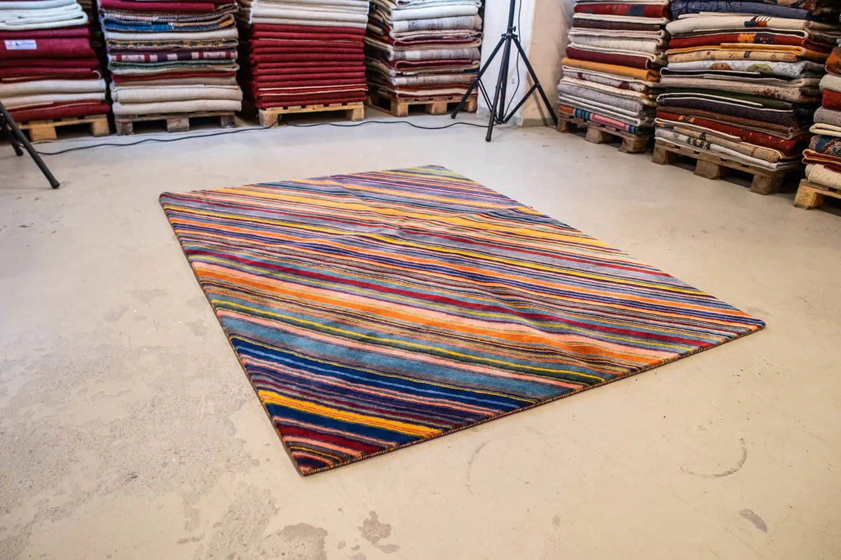 Rug on a concrete floor: long striped pattern in blue, orange, green, and red