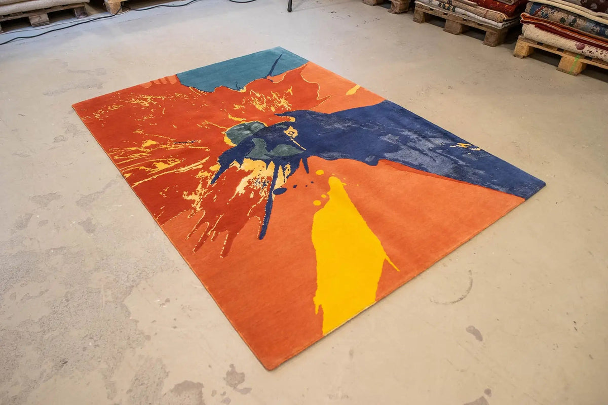 Large orange, blue, and yellow splash-patterned rug placed diagonally