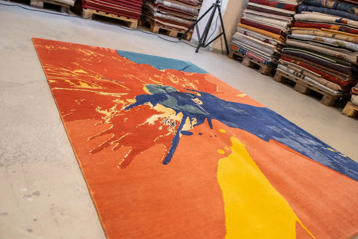 Rug in orange, blue and yellow with a large splash motif, positioned at an angle