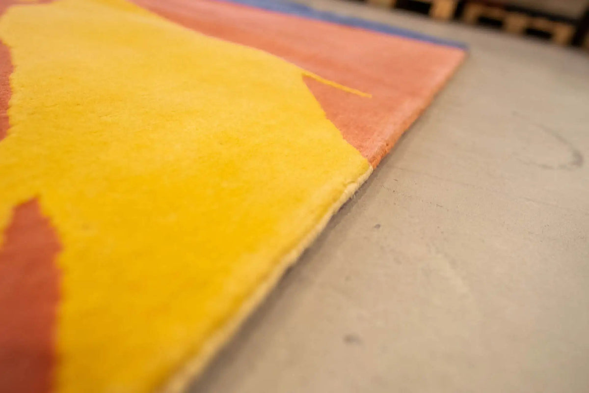 Carpet corner in the near field with a yellow and orange splash motif and border edge