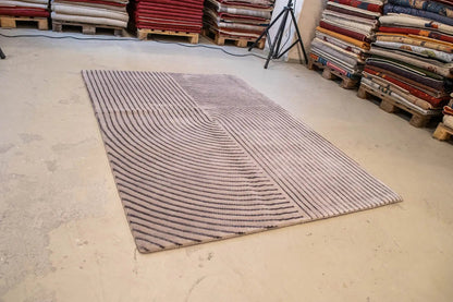 Rug on a light-colored surface, gray design with dark blue lines and curved arcs