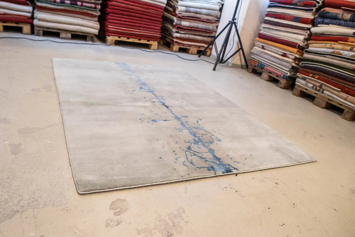 Ink-streaked carpet 153x209 cm on floor, gray with blue ink markings.