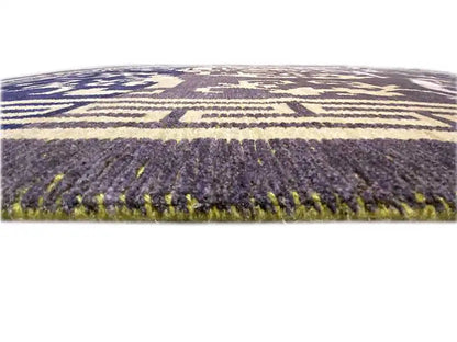 Rug: close-up with dark gray pile, blue-violet ornaments, and fringes.