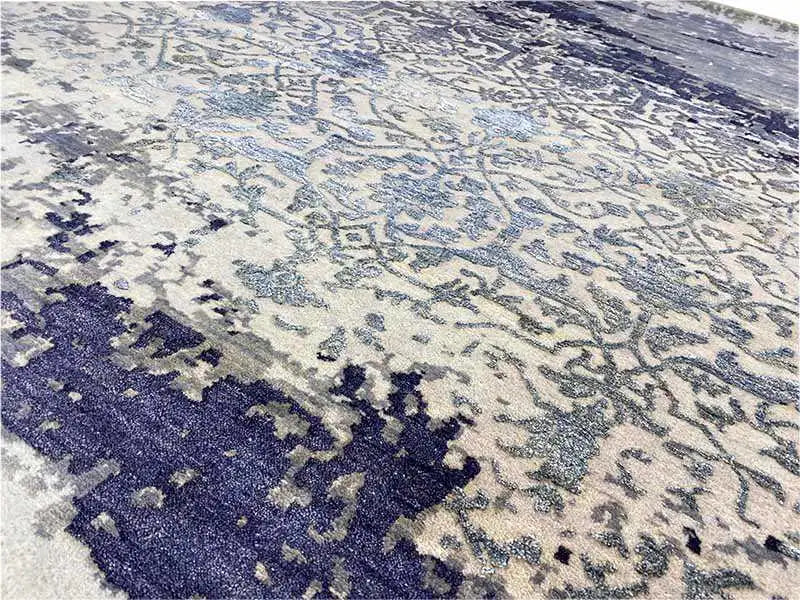 Close-up of the carpet: delicate ornamental pattern in light beige and dark blue