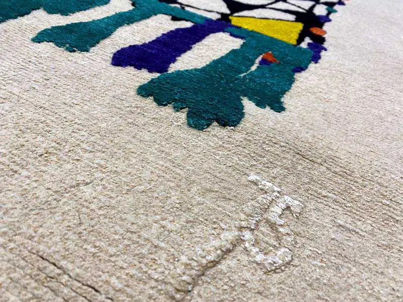 Close-up of 172x242 cm rug: beige pile with multicolored pattern elements