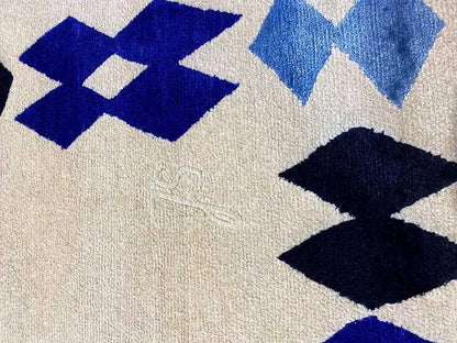 Carpet with a blue diamond pattern on a beige background, finely textured surface