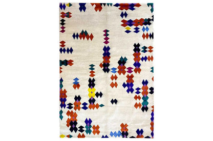 Rug with a geometric patchwork pattern in blue, red, yellow, and purple on a light background.