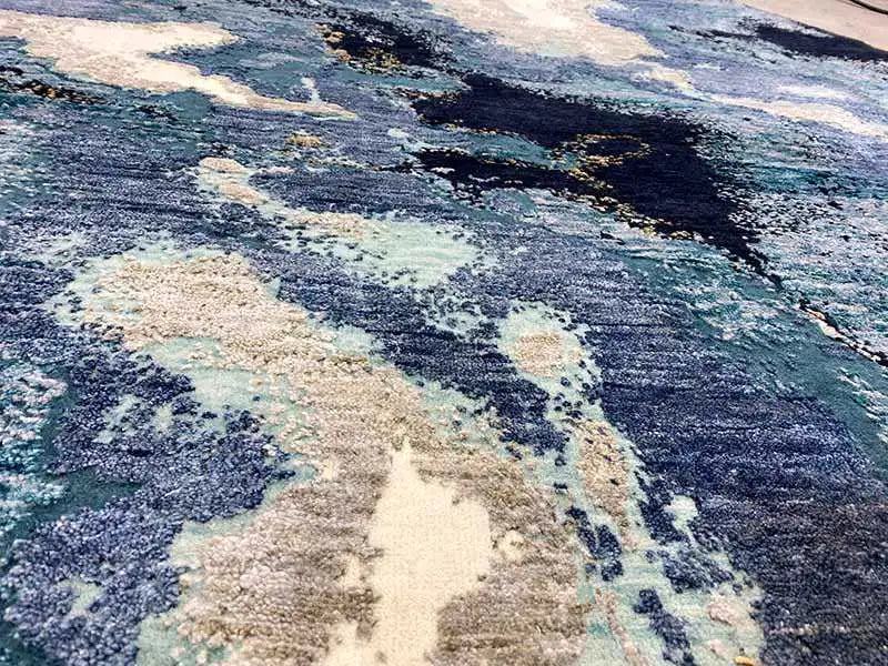 Close-up of the carpet surface: abstract blue-beige pattern with irregular gradients.