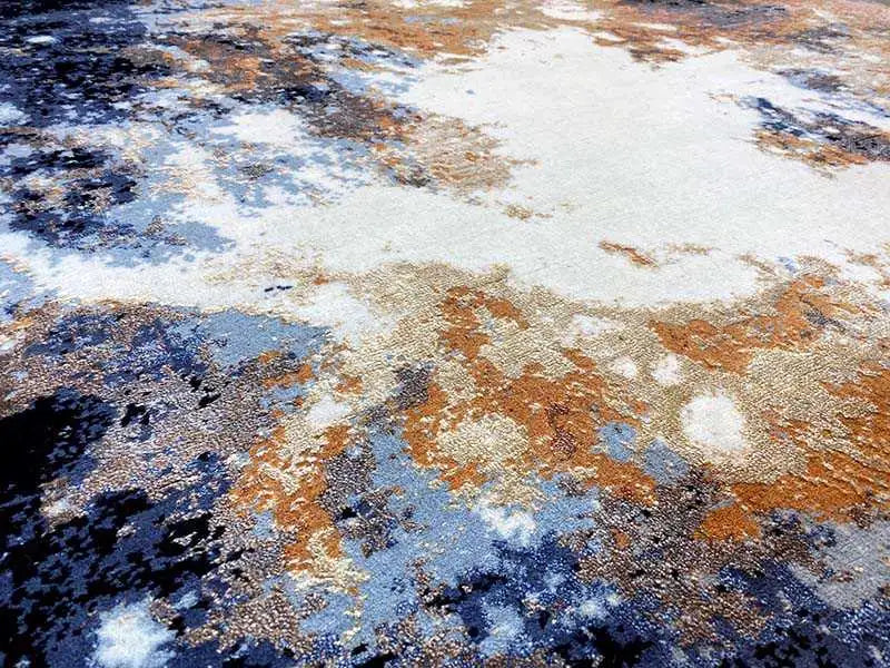 Rug surface in detail: light beige areas with speckles in blue and rust orange