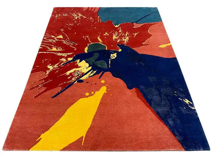 Rug with an abstract splash design in red/orange, blue, and yellow, laid flat