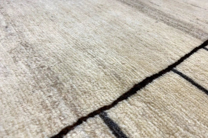 Close-up of a Gabbeh rug: light beige pile with a dark border and lines