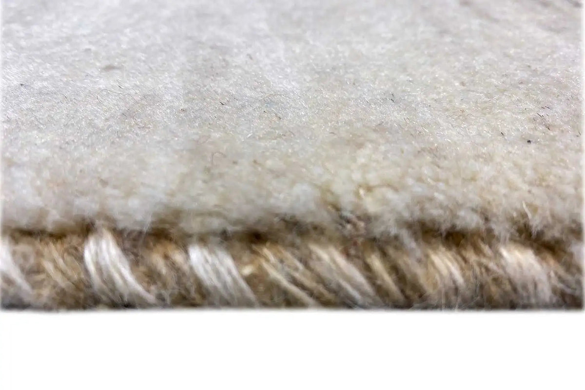 Close-up: light beige Gabbeh rug with a fluffy edge and tightly woven border