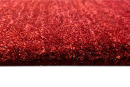 Carpet surface in burgundy with a dense pile structure along the edge
