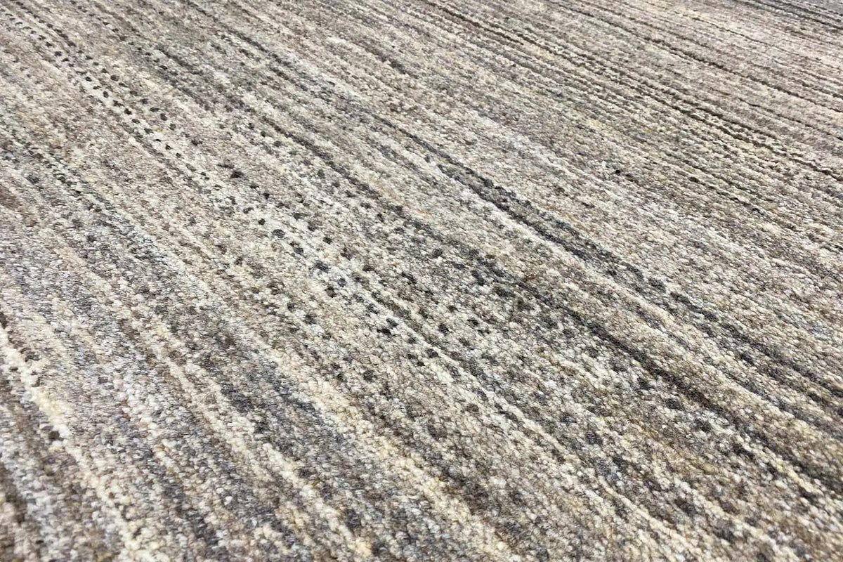 Close-up of a Gabbeh rug: gray-beige pile with long light and dark stripes