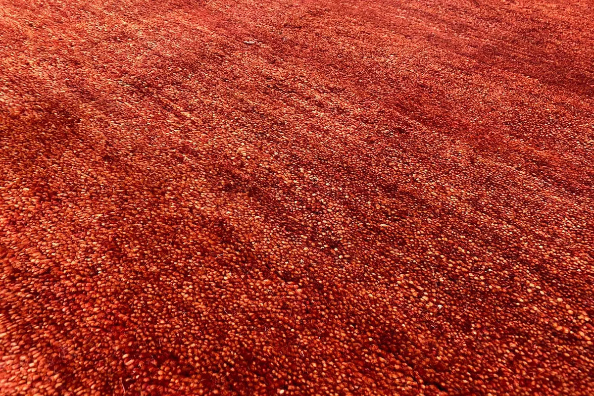 Gabbeh rug surface close-up: reddish-brown, dense low pile