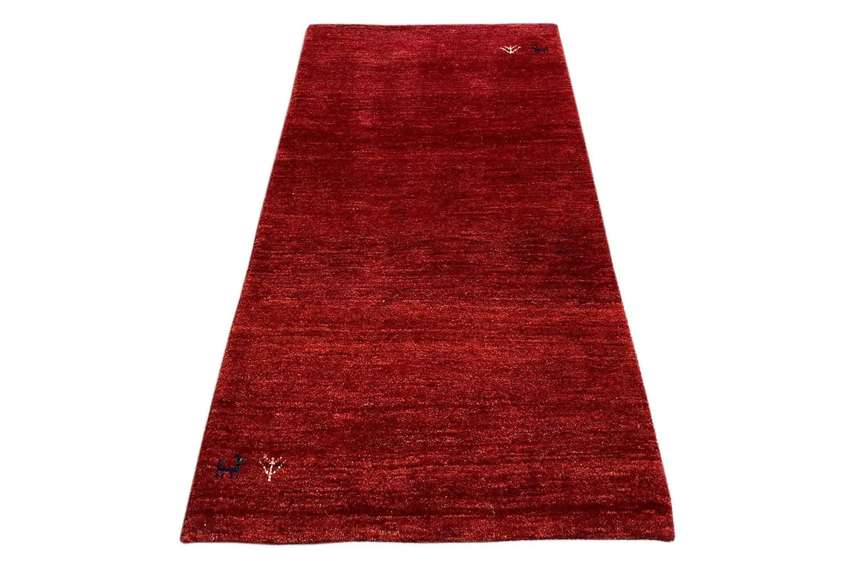 Red Gabbeh rug with a fine woven texture, angled view