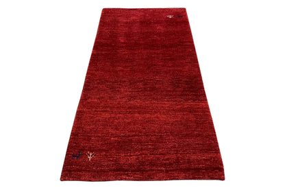 Red Gabbeh rug with a fine woven texture, angled view