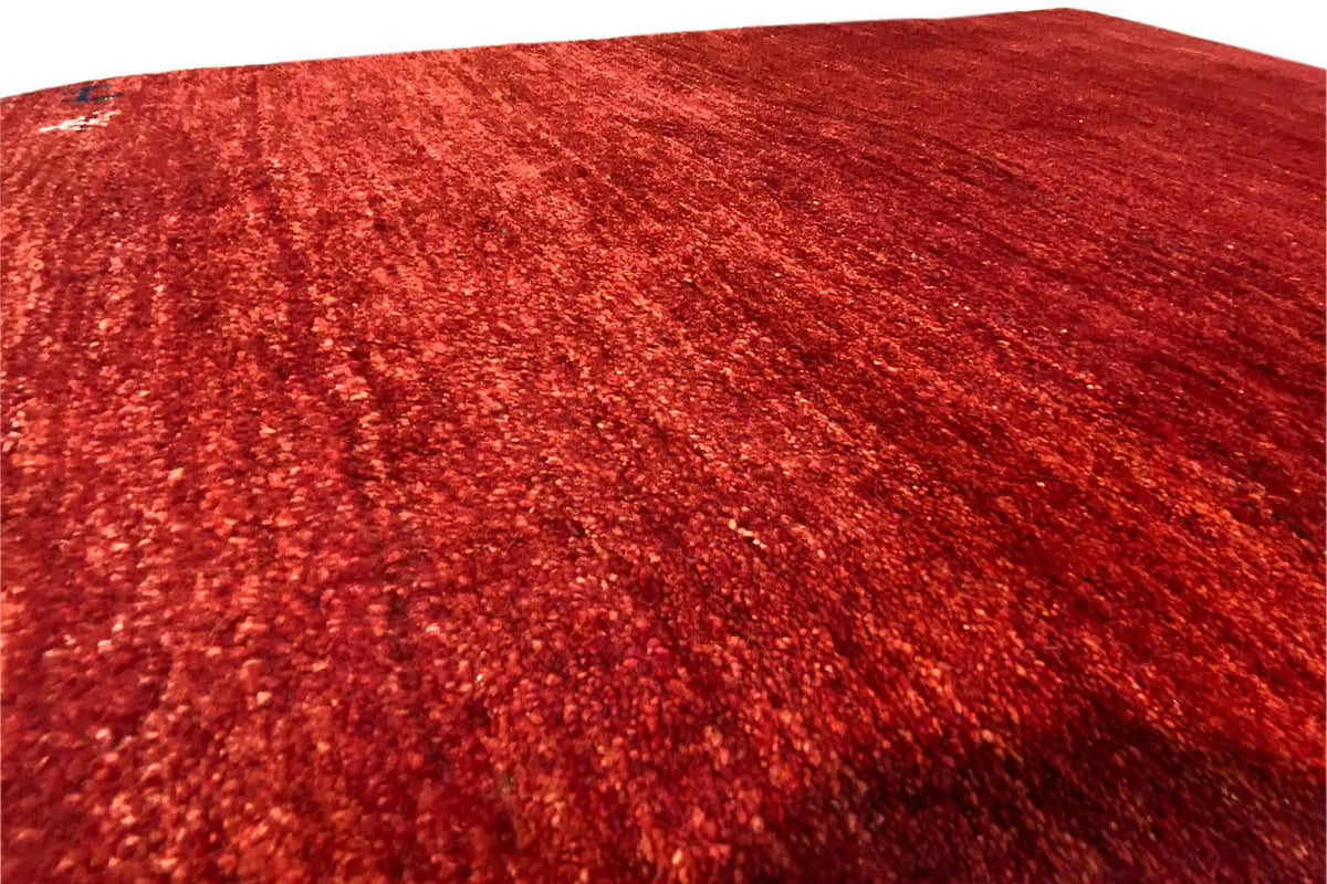 Close-up of a Gabbeh rug: red pile with an even grain pattern