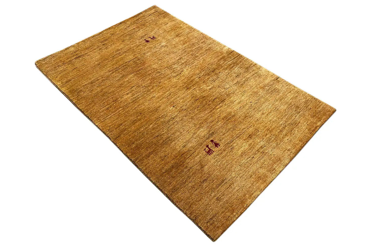 Golden-brown Gabbeh rug, laid diagonally, with small red medallions