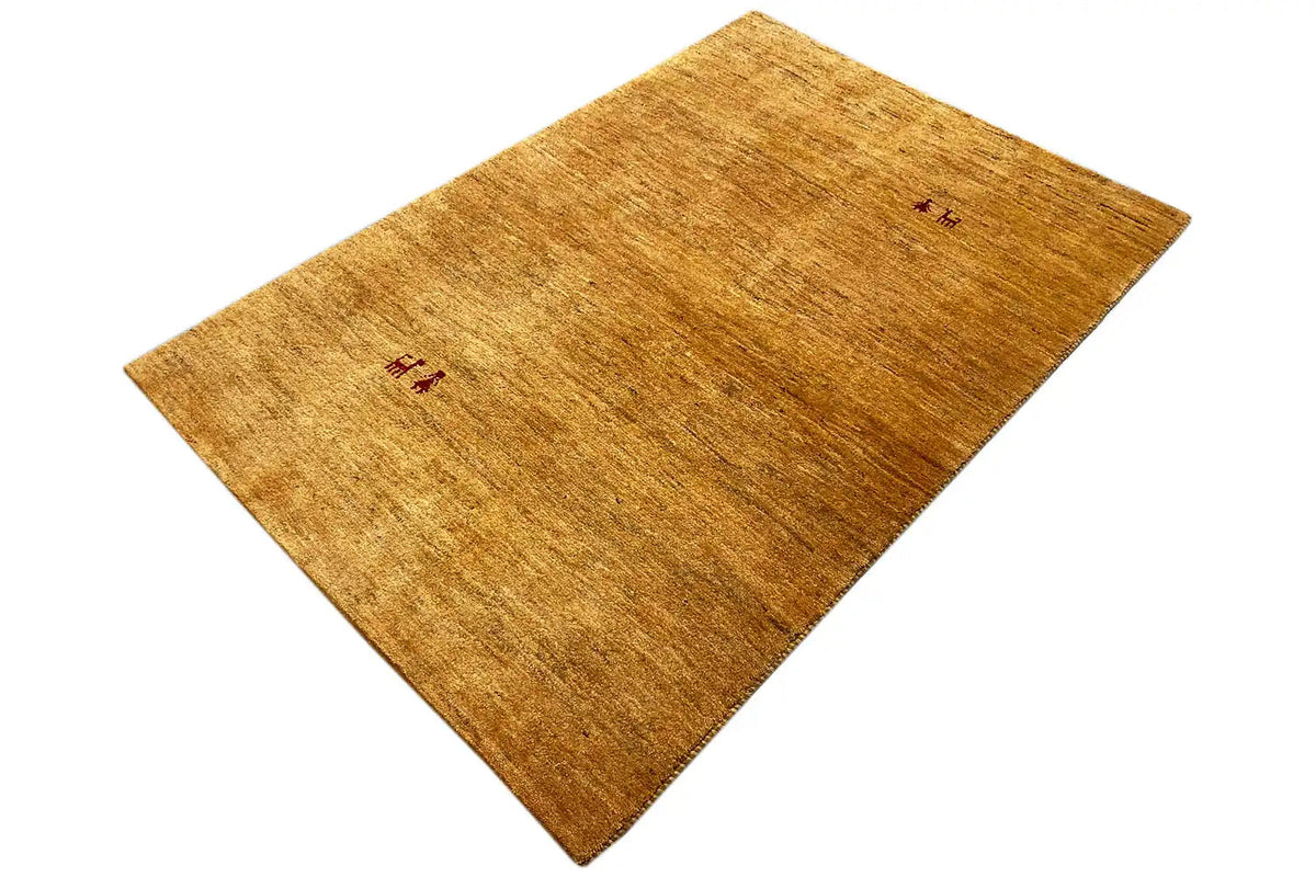 Golden-brown Gabbeh rug, laid at an angle, two small red motifs