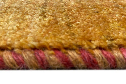 Close-up of a carpet: brown-gold woven texture with a multicolored fringe border