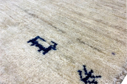 Gabbeh rug close-up: light beige with a blue pattern and pile texture