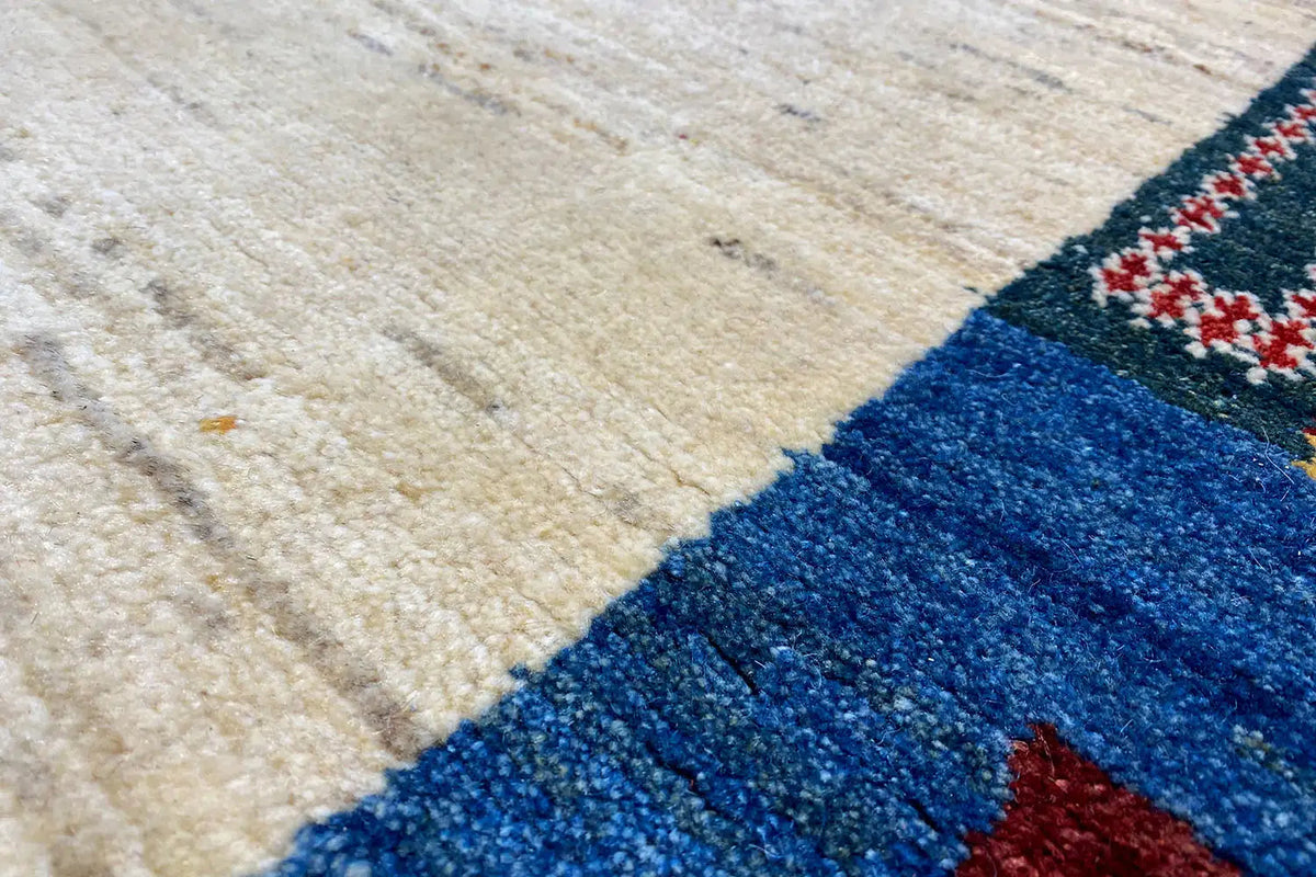 Gabbeh rug detail: woven texture with a blue border and beige center