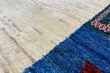 Gabbeh rug detail: woven texture with a blue border and beige center