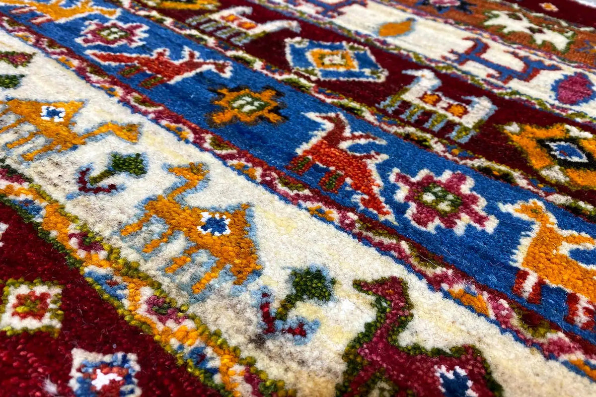 Rug with a dense pattern in blue, red, green, and orange on a cream-colored background