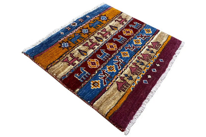 Gabbeh Lori rug in angled view with medallion and striped design, blue, burgundy, beige