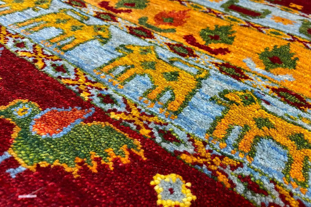 Gabbeh Lori rug 61x58 cm close-up: yellow-orange ornaments on a blue background, bordered in red