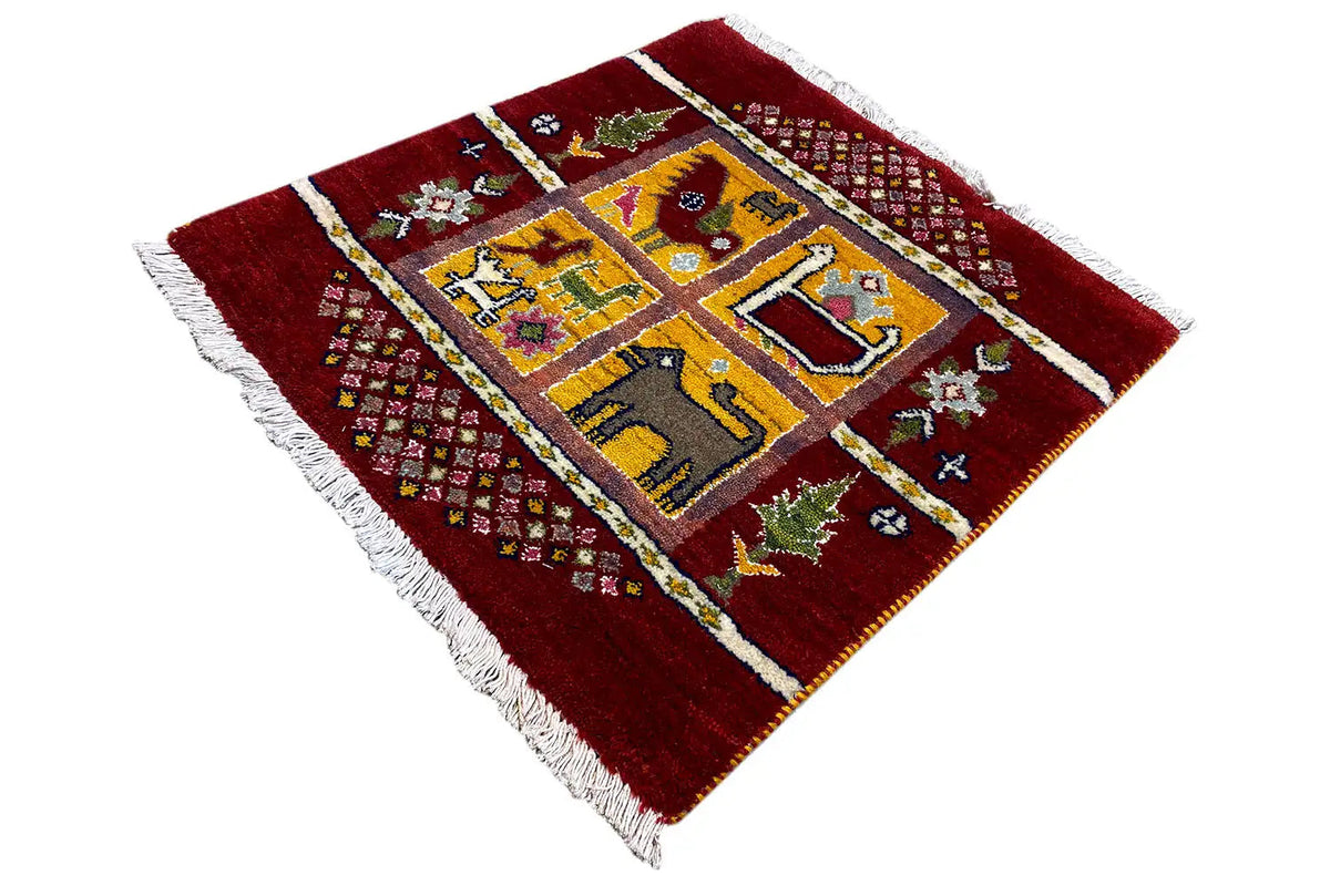Gabbeh Lori rug with a red background, yellow-blue central medallion, and white fringed border
