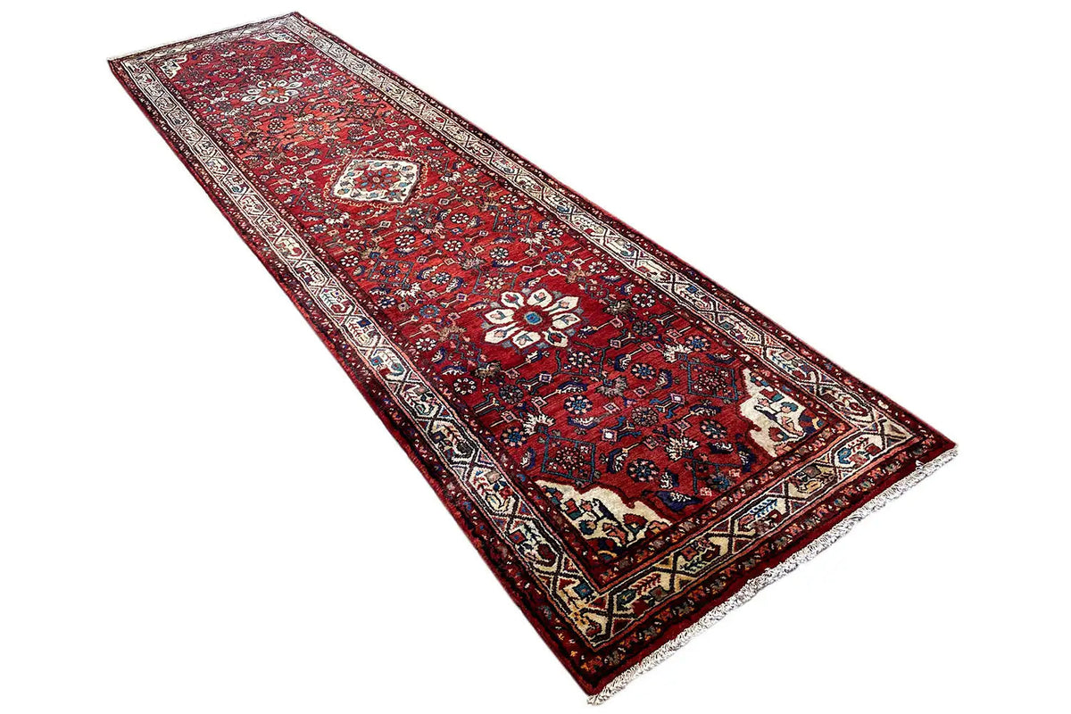 Hamadan rug angled view: red base pattern with central medallion