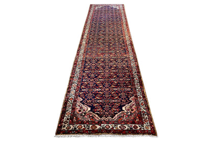 Oriental rug runner in a landscape format with a delicate red-and-blue pattern and beige central area, surrounded by a border.
