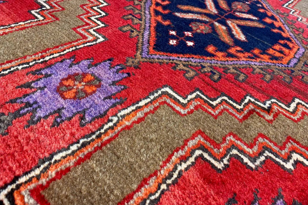 Table runner with a geometric patchwork pattern in red, blue and beige, with a border