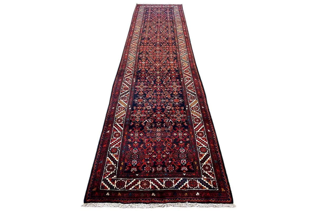 Dark patterned oriental rug runner shown at an angle, with a border and fringes