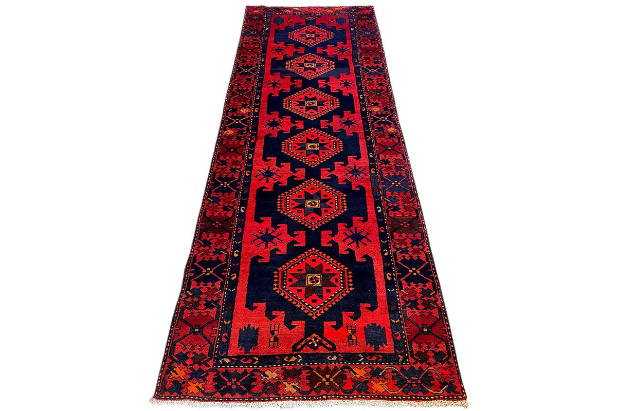 Narrow runner rug in red and dark blue with central medallions and decorative borders.