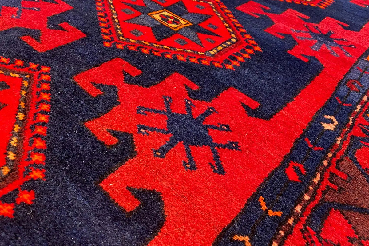 Close-up of red motifs on a dark blue background with zigzag and star patterns.