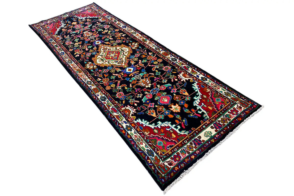 Oriental runner rug with decorative border and central medallion in red, blue, and green