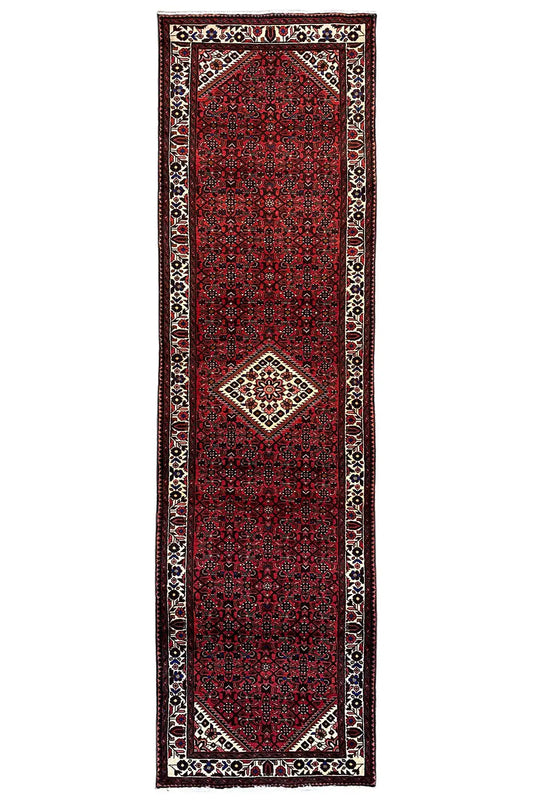 Oriental runner rug with a red central field, framed border, and small medallion