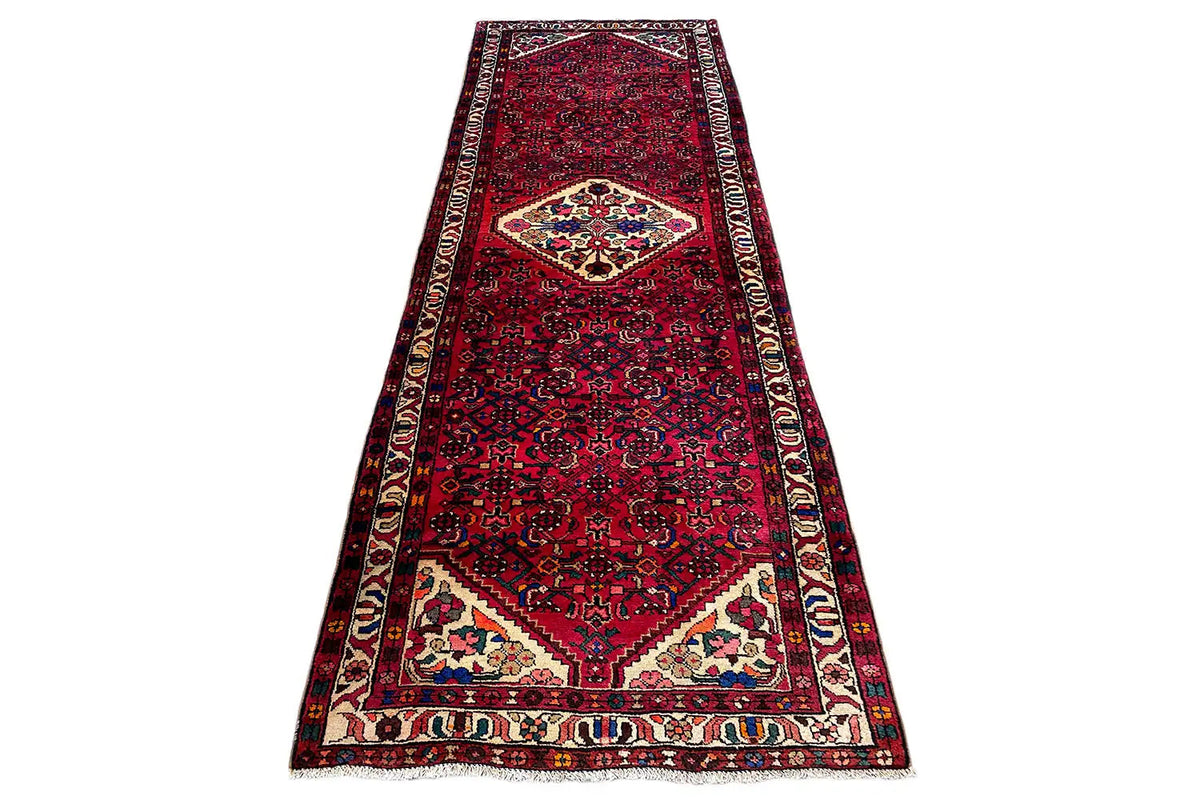 Hamadan runner in a narrow layout: red ground, central medallion, and borders along the edges