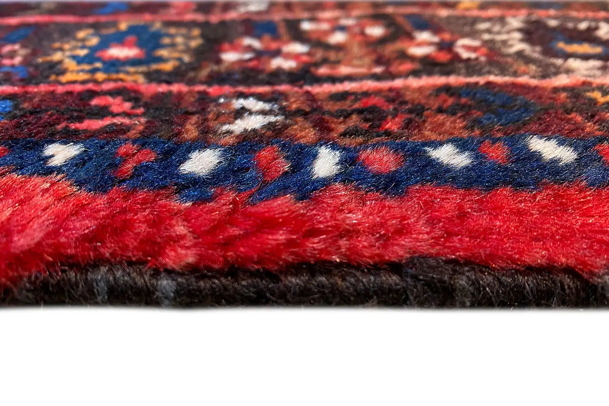 Close-up: red carpet pile with blue-and-white ornaments and a dark edge