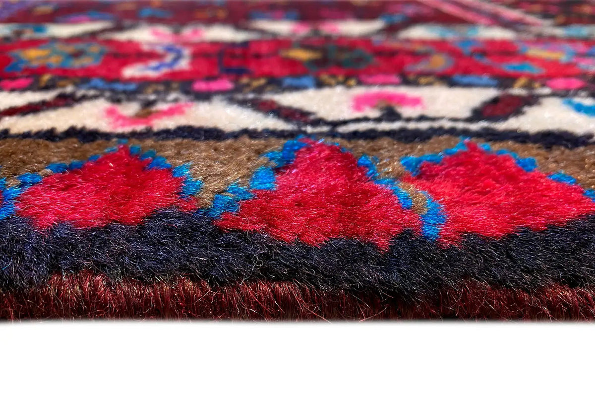 Close-up of a Hamadan rug: pile with red and blue patterns, high-contrast edges