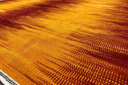 Kilim rug with an orange-yellow pattern and fine textured surface, cropped at the sides
