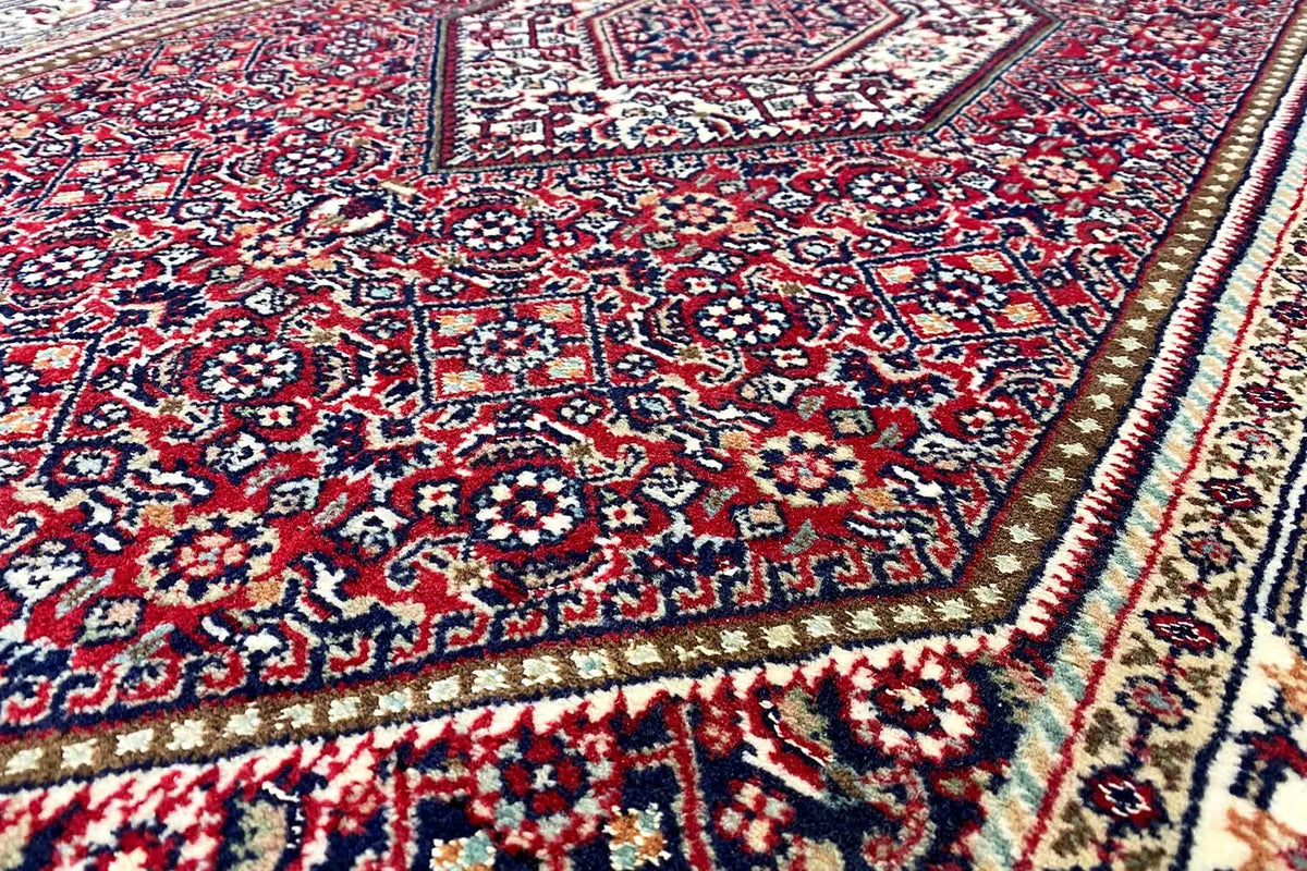 Rug with a red, blue, and cream-colored pattern, detailed view of the edge.