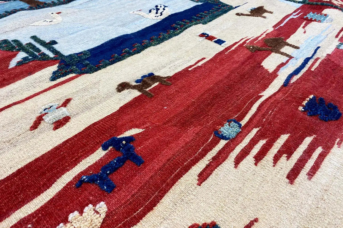 Kilim Qashqai rug detail view with red areas and blue stylized motifs